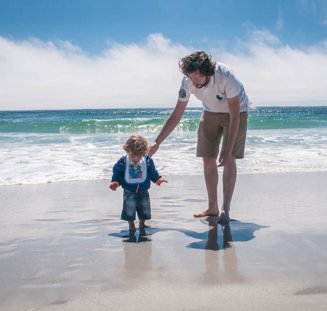 Foto de padre e hijo en la playa por Francesca Petringa en Unsplash